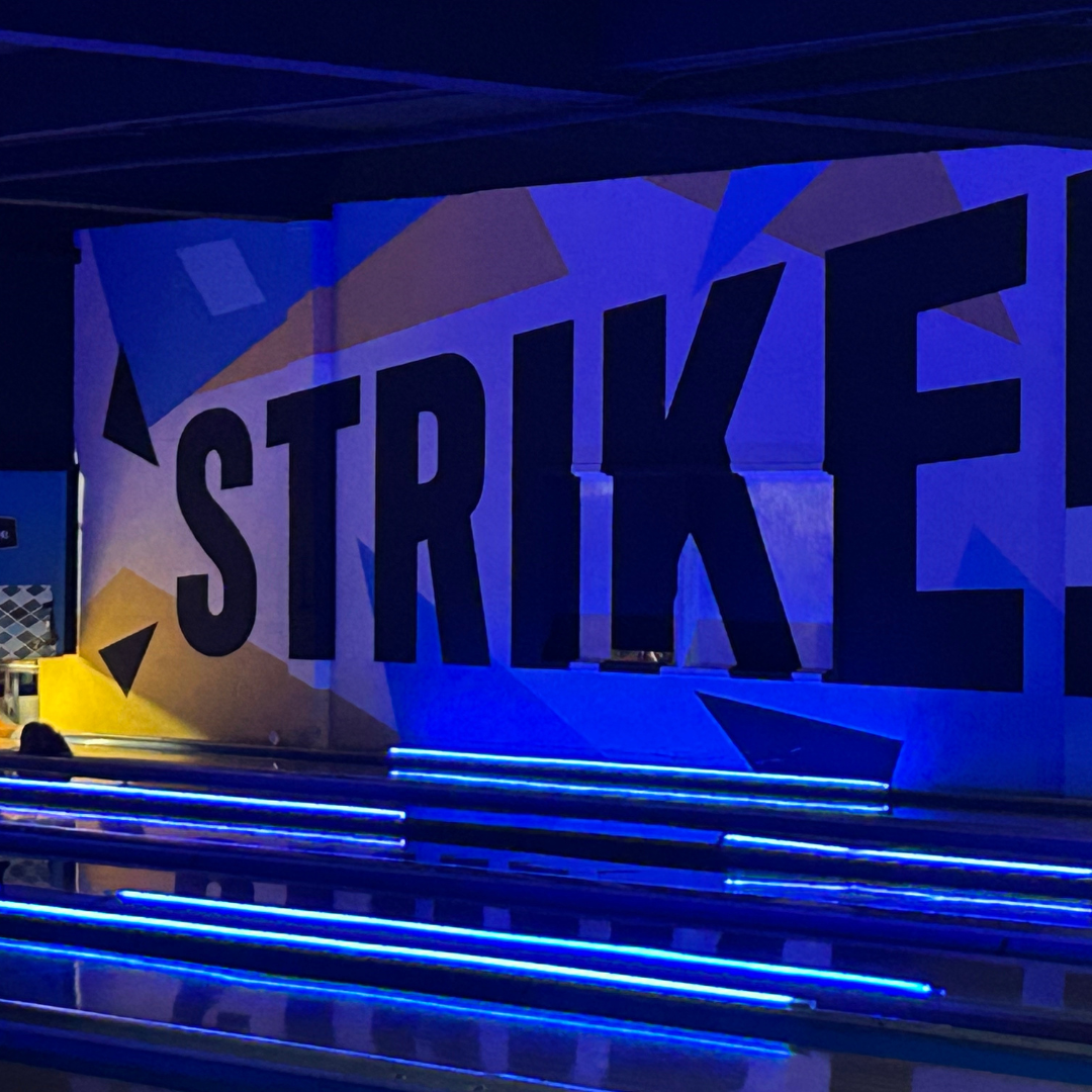 Bold mural on the wall by the bowling lanes with the word 'Strike!' at Bowlounge Dallas